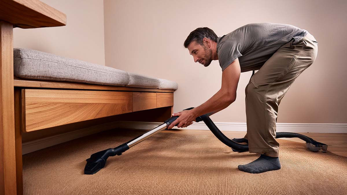 Man Vacuuming Under Furniture