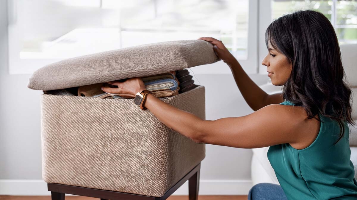 Woman Storing Clothes In Ottoman